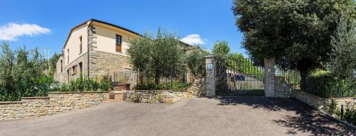 uma casa com uma cerca de pedra e uma entrada em Agriturismo Borgo tra gli Olivi em Castiglion Fiorentino
