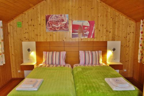 1 dormitorio con cama verde y paredes de madera en Villa Ana Margarida by Nature, en Ericeira