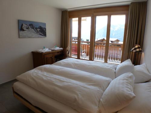 two beds in a hotel room with a large window at Chalet Bella Vista 6 in Wengen