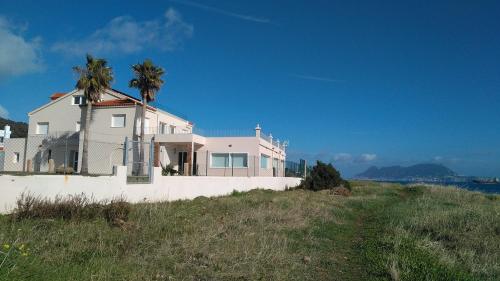 a white house on a hill with palm trees at Punta Carnero Hostal in Algeciras