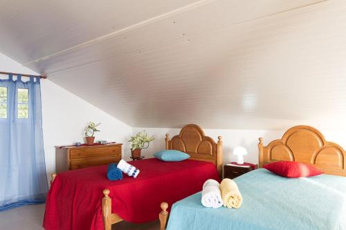 a bedroom with two beds with red and blue pillows at Casa Alto Santo António in Ponta do Sol