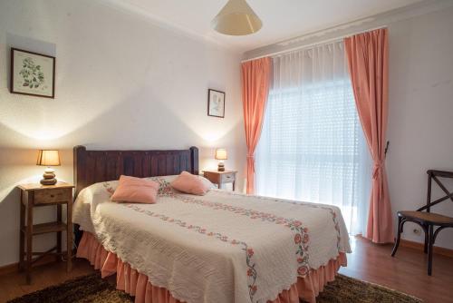 a bedroom with a bed with pink pillows and a window at Apartamento da Estação in Monção