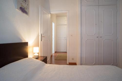 a bedroom with a white bed and a hallway at Apartamento da Estação in Monção