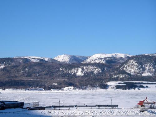 a snow covered field with mountains in the background at Chalets Condos sur le Fjord in LʼAnse-Saint-Jean
