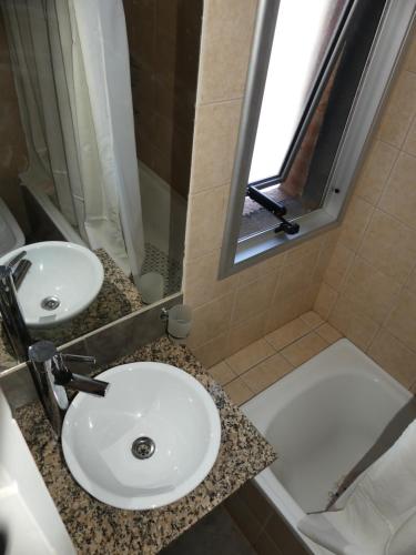 y baño con lavabo, ducha y bañera. en Departamentos Córdoba Nuevo Kaiken en Córdoba