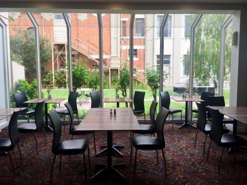 a row of tables and chairs in a room with windows at Burkes Hotel Motel in Yarrawonga