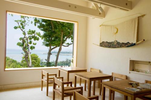 a room with tables and chairs and a large window at Kaiza in Nanjo