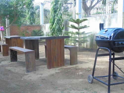 a grill and wooden benches and a table and a grill istg at Hostal Villas Mexico in San Juan del Sur