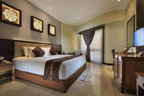 a bedroom with a large bed and a flat screen tv at Pelangi Bali Hotel & Spa in Seminyak