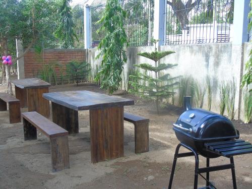 a grill and wooden tables and benches and a grill at Hostal Villas Mexico in San Juan del Sur