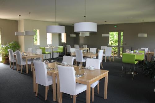 une salle à manger avec des tables et des chaises blanches dans l'établissement The Originals Boutique, Hôtel Marytel, Montbrison (Inter-Hotel), à Montbrison