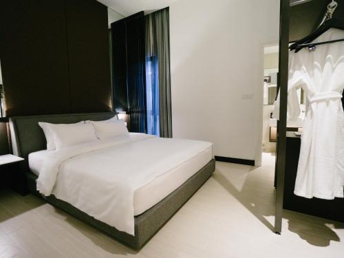 a bedroom with a white bed and a dress on a rack at Avillion Cameron Highlands in Cameron Highlands