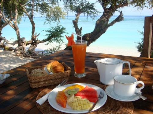 un tavolo con un piatto di frutta e una bevanda di Alam Gili Trawangan by Mahaputra a Gili Trawangan