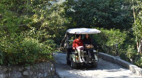 two people riding a golf cart down a road at Veda5 Ayurveda & Yoga Retreat in Rishīkesh