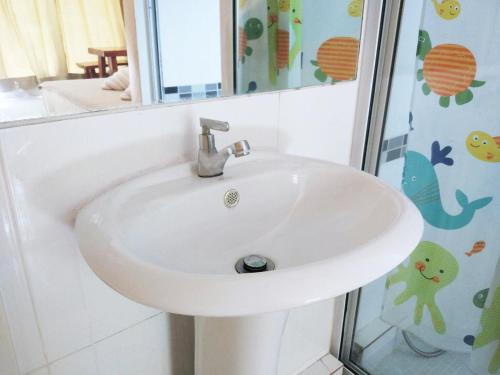 lavabo blanco en el baño con espejo en Great Hill Resort, en Langu