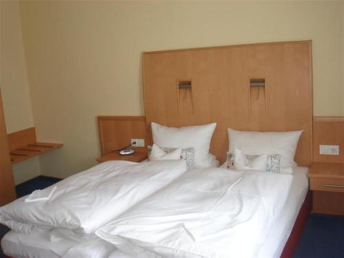 a large bed with white sheets and a wooden headboard at Tannenheim in Boppard