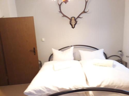 two beds with white sheets and a deer head on the wall at 3 Sterne Ferienwohnungen Wachter in Bischofsgrün