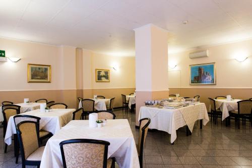 un restaurante con mesas y sillas con mantel blanco en Piccolo Hotel en Milán
