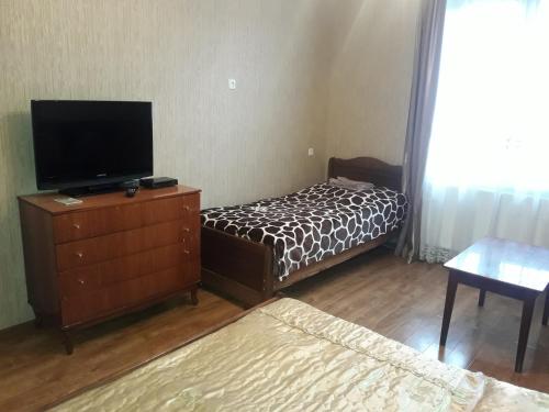 1 dormitorio con 1 cama y vestidor con TV en zeiko s guesthouse, en Borjomi