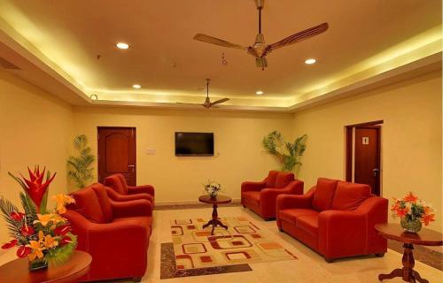 a living room with red chairs and a ceiling fan at Dhanunjayas Luxury Hotel in Hosūr