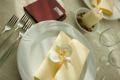 ein Tisch mit einem weißen Teller mit einer Blume darauf in der Unterkunft Hotel Consuelo in Riccione
