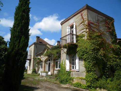 una vecchia casa con l'edera sul lato. di Chambres d'Hôtes Le Loubet a LʼIsle-Jourdain