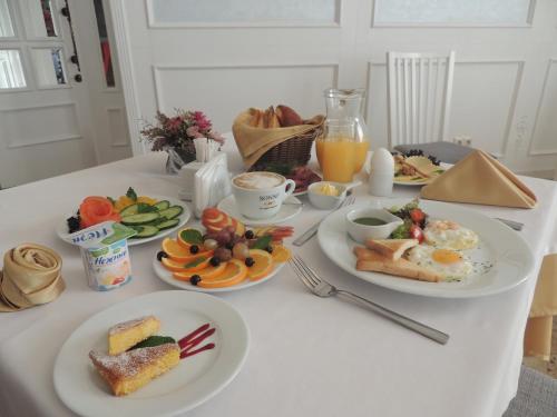 un tavolo bianco con piatti per la colazione di Hotel Monaco a Astana