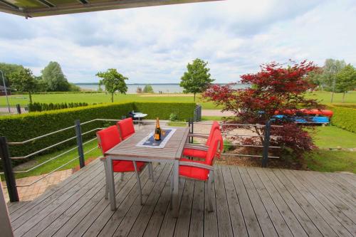a wooden table with four red chairs on a deck at Haus STRANDLAeUFER _ EG_Fewo in Göhren-Lebbin