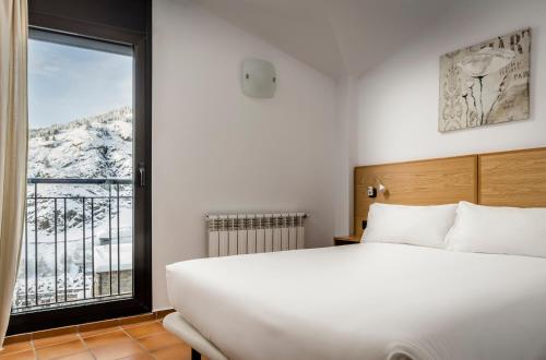 - une chambre avec un grand lit blanc et une fenêtre dans l'établissement Apartamentos Prat de les Molleres, à Soldeu