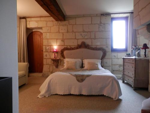 a bedroom with a bed and a stone wall at le prieuré in Montsoreau