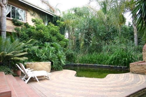 a patio with two chairs and a pond in front of a house at Crocodile Lodge cc in Midrand