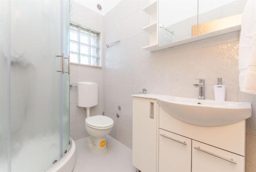 Baño blanco con lavabo y aseo en Apartments Rose, en Sućuraj