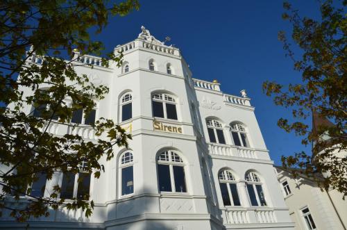 ein hohes weißes Gebäude mit einem Uhrturm in der Unterkunft Villa Sirene - Wohnung 08 in Binz