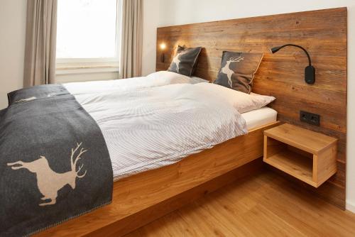 a bedroom with a bed with a wooden headboard at Ferienwohnung Kraus in Tiefenbach bei Oberstdorf