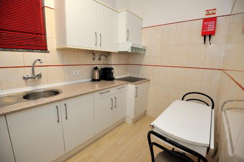 una piccola cucina con armadi bianchi e lavandino di Sunhouse a Luz