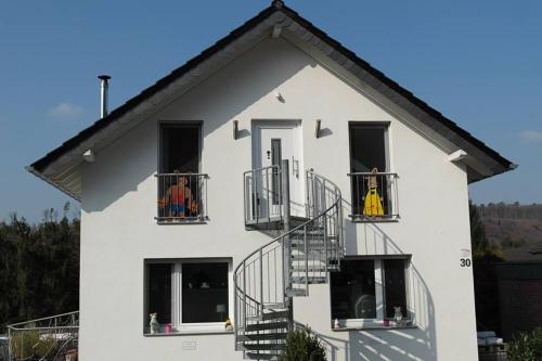 a white house with two people on their balconies at Haus am Hang; Ferienwohnung Fernblick in Stolberg