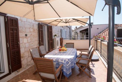 eine Terrasse mit einem Tisch, Stühlen und einem Sonnenschirm in der Unterkunft Holiday Home Meditation in Hvar