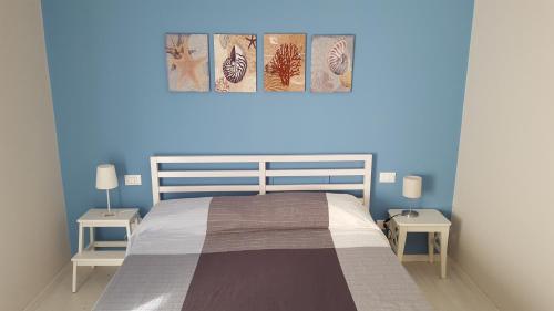 - une chambre bleue avec un lit et deux tables dans l'établissement Galù Guest House Gaeta, à Gaète