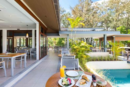an outdoor patio with tables and chairs and a pool at Dewa Phuket Resort & Villas in Nai Yang Beach