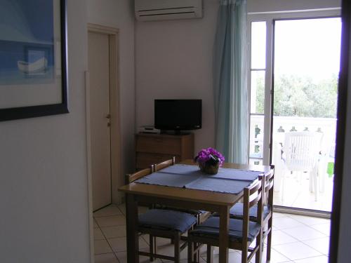 Un comedor con una mesa con sillas y un televisor. en Apartments Paloma Blanca, en Medulin
