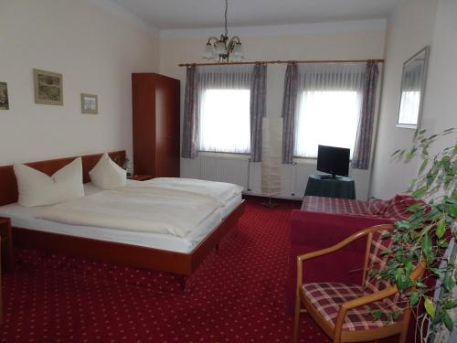 a bedroom with a bed and a chair and windows at Hotel & Gasthof Zum Löwen in Eisenach