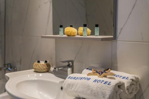 La salle de bains est pourvue d'un lavabo, d'un miroir et de serviettes. dans l'établissement Kordistos Hotel, à Kefalos