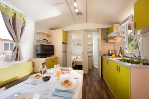 a kitchen with yellow cabinets and a table with food at Sirena Mobile Homes in Novigrad Istria