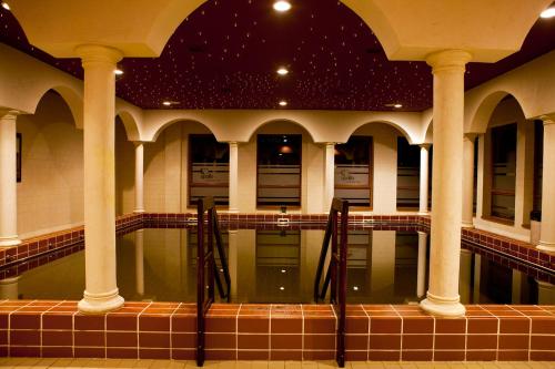 a swimming pool in a building with columns at Apollo Wellness Club in Sîngeorgiu de Mureş