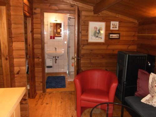 ein Bad mit einem roten Stuhl und einer Dusche in der Unterkunft Ferienhütte Stephanie in Niederschlettenbach