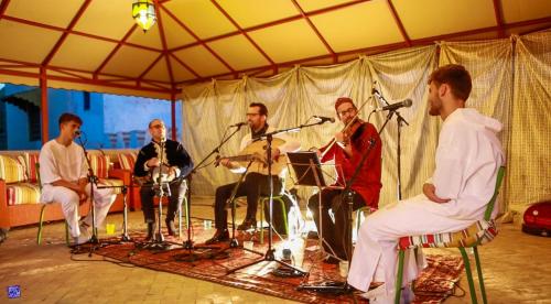 un grupo de hombres sentados en un escenario con instrumentos en Riad Jardin Des Biehn, en Fez