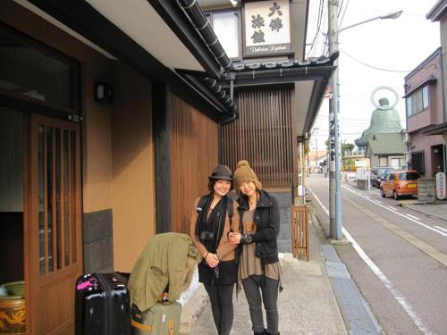 two women standing on a sidewalk next to a building at Daibutsu Ryokan in Takaoka