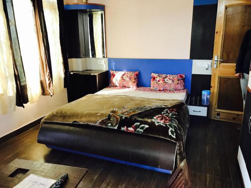 a bedroom with a bed with a blue headboard at RidgeView Homestay near Lakkar Bazar in Shimla