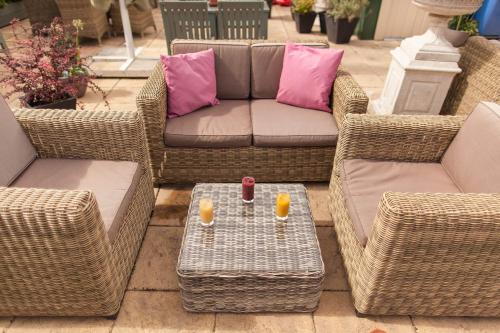 a patio with wicker chairs and a couch and a table at The Ormond At Tetbury in Tetbury