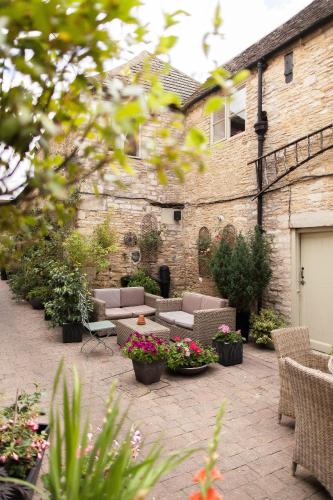 a patio with couches and flowers in front of a building at The Ormond At Tetbury in Tetbury